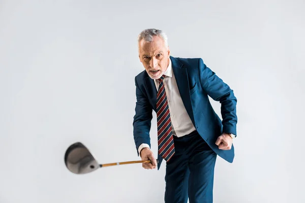 Selective focus of concentrated mature businessman holding golf club while playing isolated on grey — Stock Photo