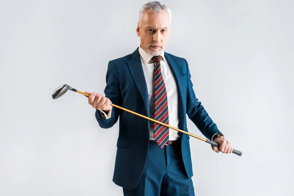 Serious mature man in suit holding golf club isolated on grey — Stock Photo