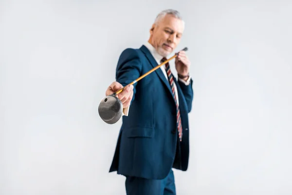 Selective focus of mature man in suit looking at golf club isolated on grey — Stock Photo