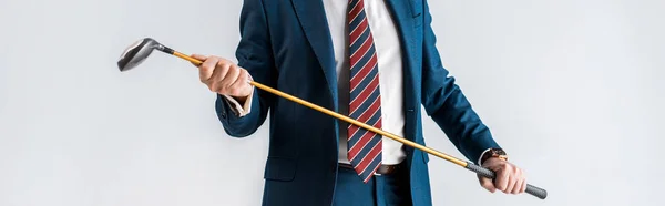 Panoramic shot of mature man in suit holding golf club isolated on grey — Stock Photo