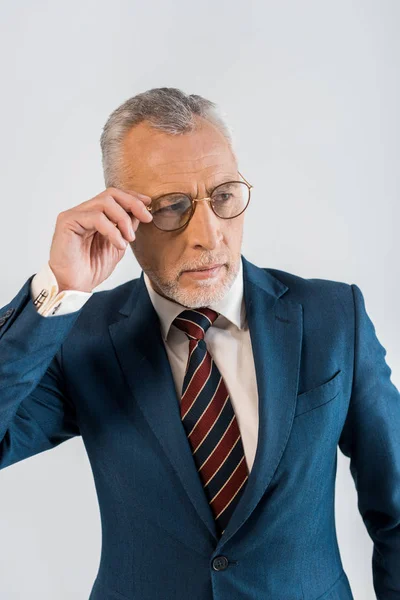 Maturo uomo d'affari toccando occhiali mentre in piedi isolato su grigio — Foto stock