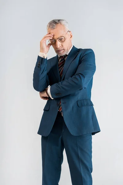 Tired mature businessman in suit having headache while standing isolated on grey — Stock Photo