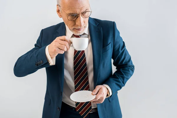 Vue aérienne de l'homme d'affaires mature tenant soucoupe et tasse isolé sur gris — Photo de stock