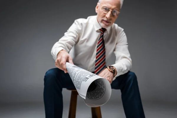 Focalizzazione selettiva di giornale in mano di uomo d'affari maturo su grigio — Foto stock