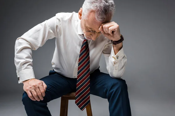 Засмучений середнього віку бізнесмен в офіційному одязі на сірому — стокове фото