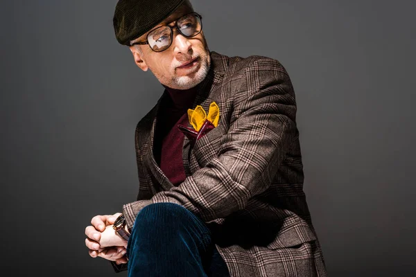 Homem maduro na moda e pensativo em boné e óculos em cinza — Fotografia de Stock