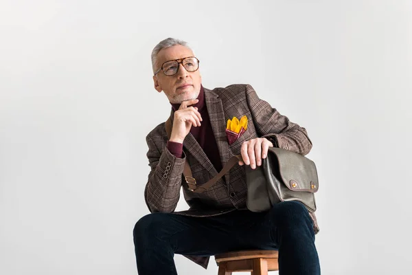 Elegante uomo maturo seduto sulla sedia e pensare isolato sul grigio — Foto stock