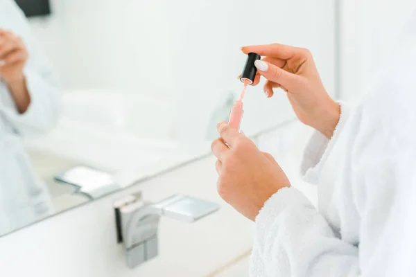 Foyer sélectif de jeune femme adulte tenant gloss lèvre dans la salle de bain — Photo de stock