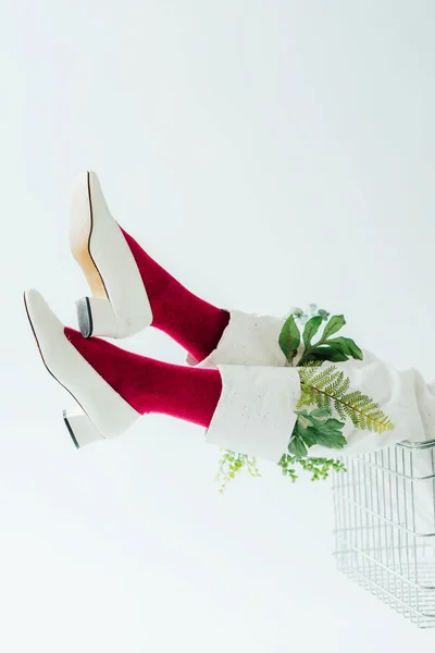 Vista recortada de la mujer en pantalones blancos con hojas verdes y zapatos elegantes aislados en blanco - foto de stock