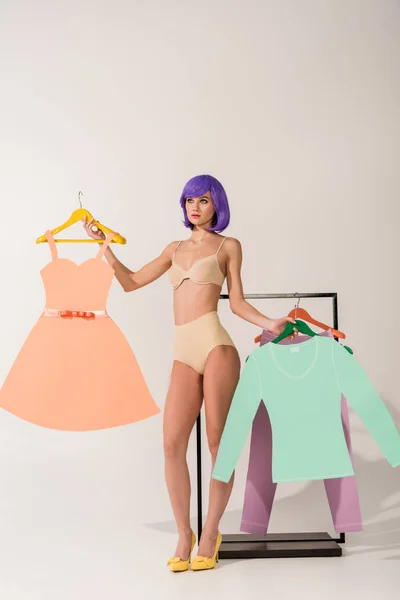 Beautiful girl with purple hair in underwear posing with colorful paper clothes on white — Stock Photo