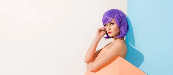 Tiro panorâmico de menina bonita com cabelo roxo coberto de folha de papel de coral posando em azul e branco com espaço de cópia — Fotografia de Stock