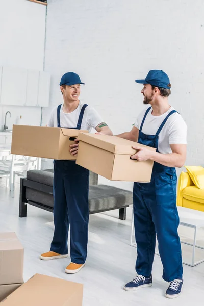 Two smiling movers transporting cardboard boxes in apartment — Stock Photo