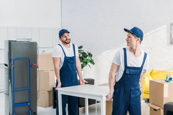 Dois movers em tabela de transporte uniforme no apartamento — Fotografia de Stock