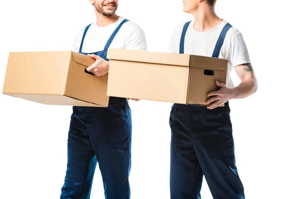 Обрезанный вид двух грузчиков, перевозящих картонные коробки, изолированные на белом — стоковое фото