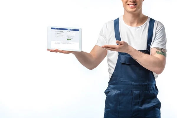 Ausgeschnittene Ansicht eines lächelnden Mover, der gestikuliert und ein digitales Tablet mit Facebook-App auf dem Bildschirm präsentiert, isoliert auf Weiß — Stockfoto