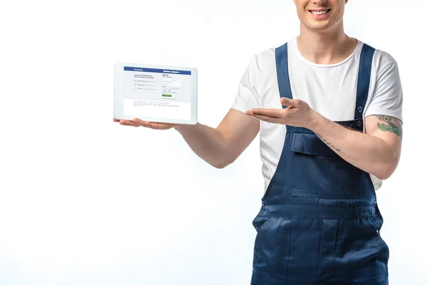 Vista recortada de mover sonriente gesto y la presentación de tableta digital con aplicación de Facebook en la pantalla aislada en blanco - foto de stock