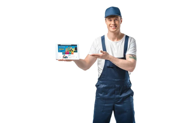 Handsome smiling mover gesturing with hand while presenting digital tablet with amazon app on screen isolated on white — Stock Photo