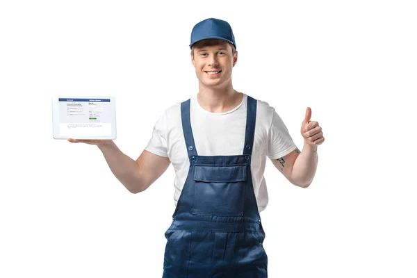 Handsome smiling mover showing thumb up and presenting digital tablet with facebook app on screen isolated on white — Stock Photo
