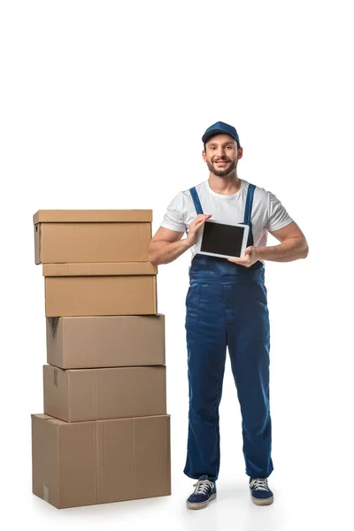 Mover with cardboard boxes looking at camera and presenting digital tablet with blank screen isolated on white — Stock Photo