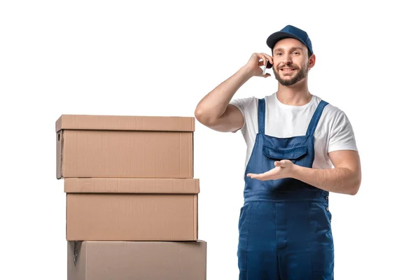 Bonito sorrindo mover com caixas de papelão falando no smartphone e gesticulando com a mão isolada no branco — Fotografia de Stock