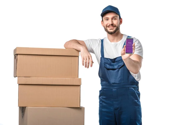 Handsome mover looking at camera and presenting smartphone with instagram app on screen isolated on white — Stock Photo