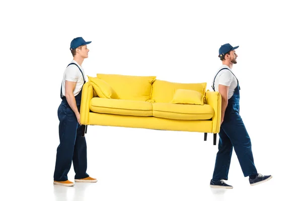 Seitenansicht von zwei Mover, die gelbes Sofa auf weißem transportieren — Stockfoto