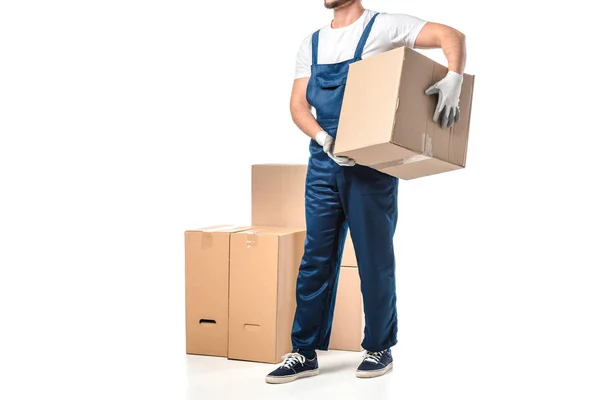 Vista cortada de mover em uniforme transportando caixa de papelão isolado em branco com espaço de cópia — Fotografia de Stock