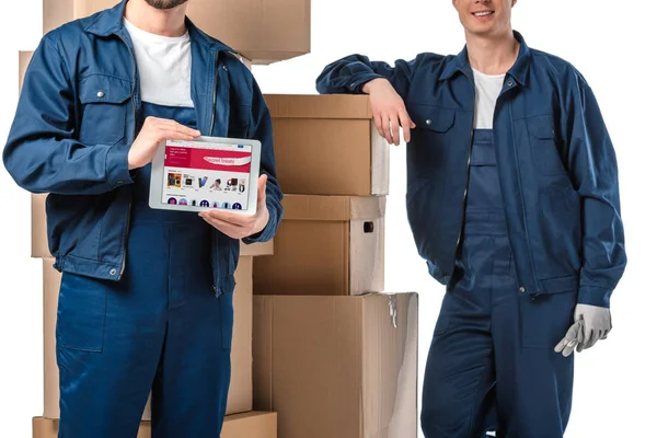 Cropped view of two movers with cardboard boxes presenting digital tablet with ebay app on screen isolated on white — Stock Photo