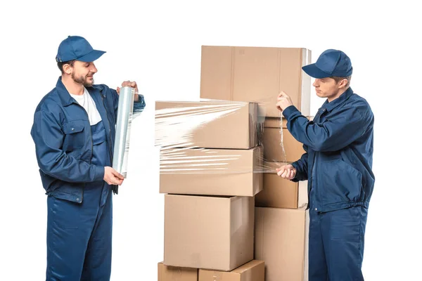 Deux déménageurs enveloppant boîtes en carton avec rouleau de film étirable isolé sur blanc — Photo de stock