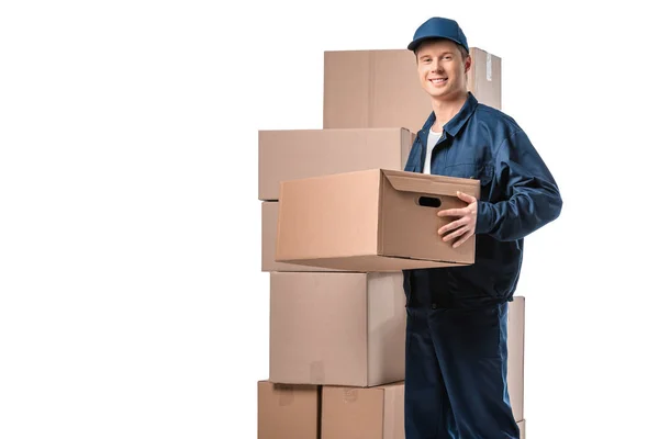 Guapo mover en uniforme llevando caja de cartón y mirando a la cámara aislada en blanco con espacio de copia - foto de stock