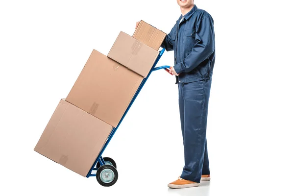 Vista cortada de mover em caixas de papelão de transporte uniforme no caminhão de mão isolado em branco — Fotografia de Stock