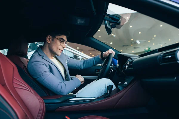 Hombre exitoso en gafas que sostienen el volante en automóvil - foto de stock