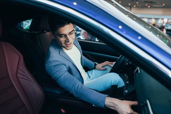 Селективный фокус успешного счастливого человека в очках, сидящего в машине — стоковое фото
