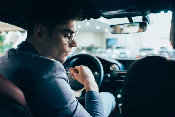 Selective focus of successful man in glasses sitting in automobile — Stock Photo