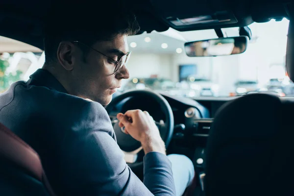 Enfoque selectivo del hombre exitoso en gafas sentado en el automóvil - foto de stock