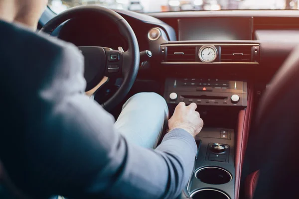Cropped view of man sitting in modern automobile and holding manual transmission — Stock Photo