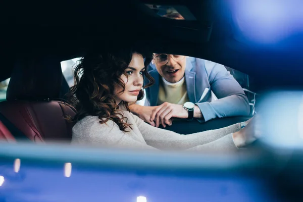 Foco seletivo de mulher atraente sentado no automóvel perto de homem alegre — Fotografia de Stock
