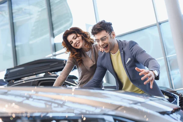 Selective focus of happy man and girl smiling while looking at car — Stock Photo