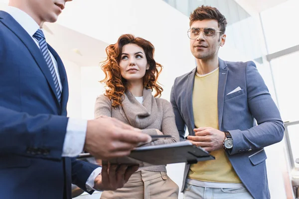 Messa a fuoco selettiva di uomo e donna guardando rivenditore di auto in possesso di appunti in auto showroom — Foto stock