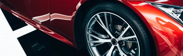 Панорамный снимок нового блестящего красного автомобиля с металлическим колесом — стоковое фото