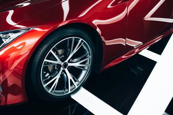 Shiny new red automobile with metallic wheel in car showroom — Stock Photo