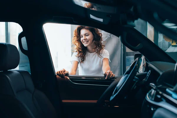 Selektiver Fokus einer fröhlich gelockten Frau, die in der Nähe von Autos steht — Stockfoto