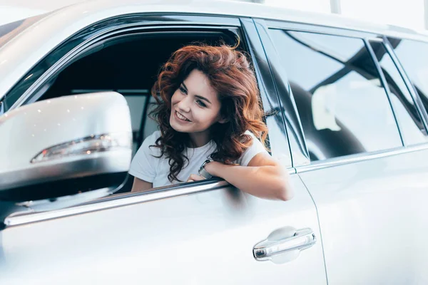 Selective focus of cheerful curly woman sitting and smiling in automobile — Stock Photo