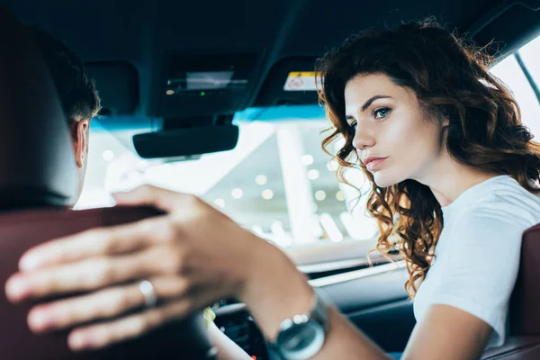 Selective focus of curly woman sitting near man in automobile — Stock Photo