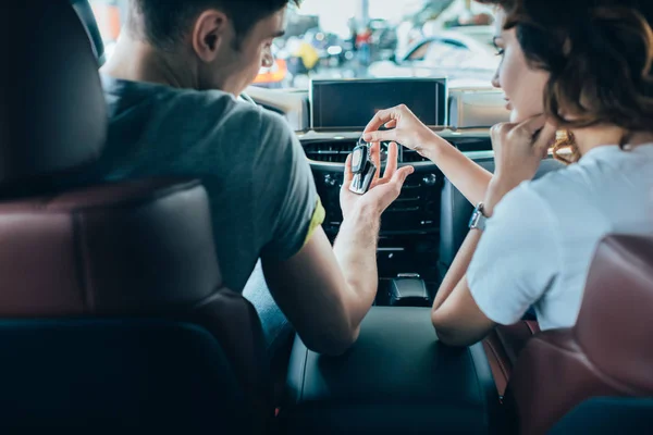 Selective focus of girl giving keys to man while sitting in automobile — Stock Photo