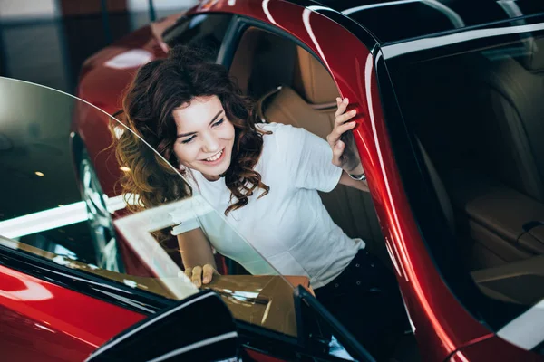 Selektiver Fokus einer lächelnden hübschen Frau im neuen roten Auto — Stockfoto