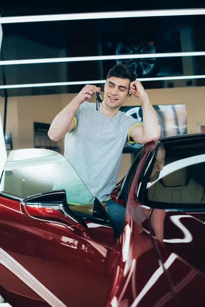 Enfoque selectivo de hombre feliz sosteniendo las llaves del coche mientras está de pie cerca de coche nuevo - foto de stock