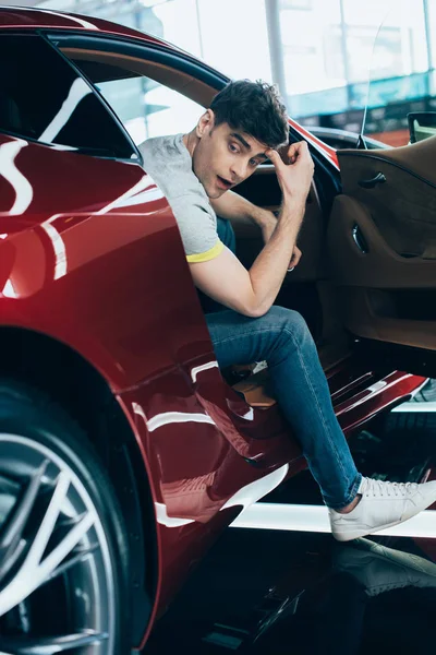 Selective focus of handsome man sitting in new red car — Stock Photo