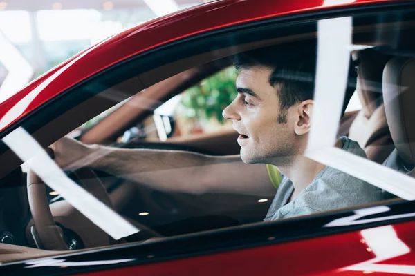 Foco seletivo do homem feliz sentado no volante no carro novo — Fotografia de Stock