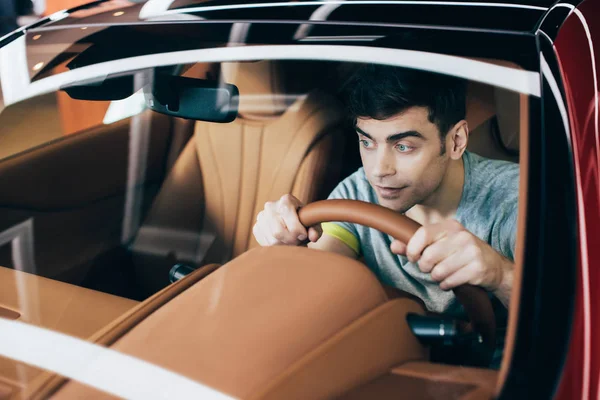 Foyer sélectif de bel homme souriant assis au volant dans une nouvelle voiture — Photo de stock